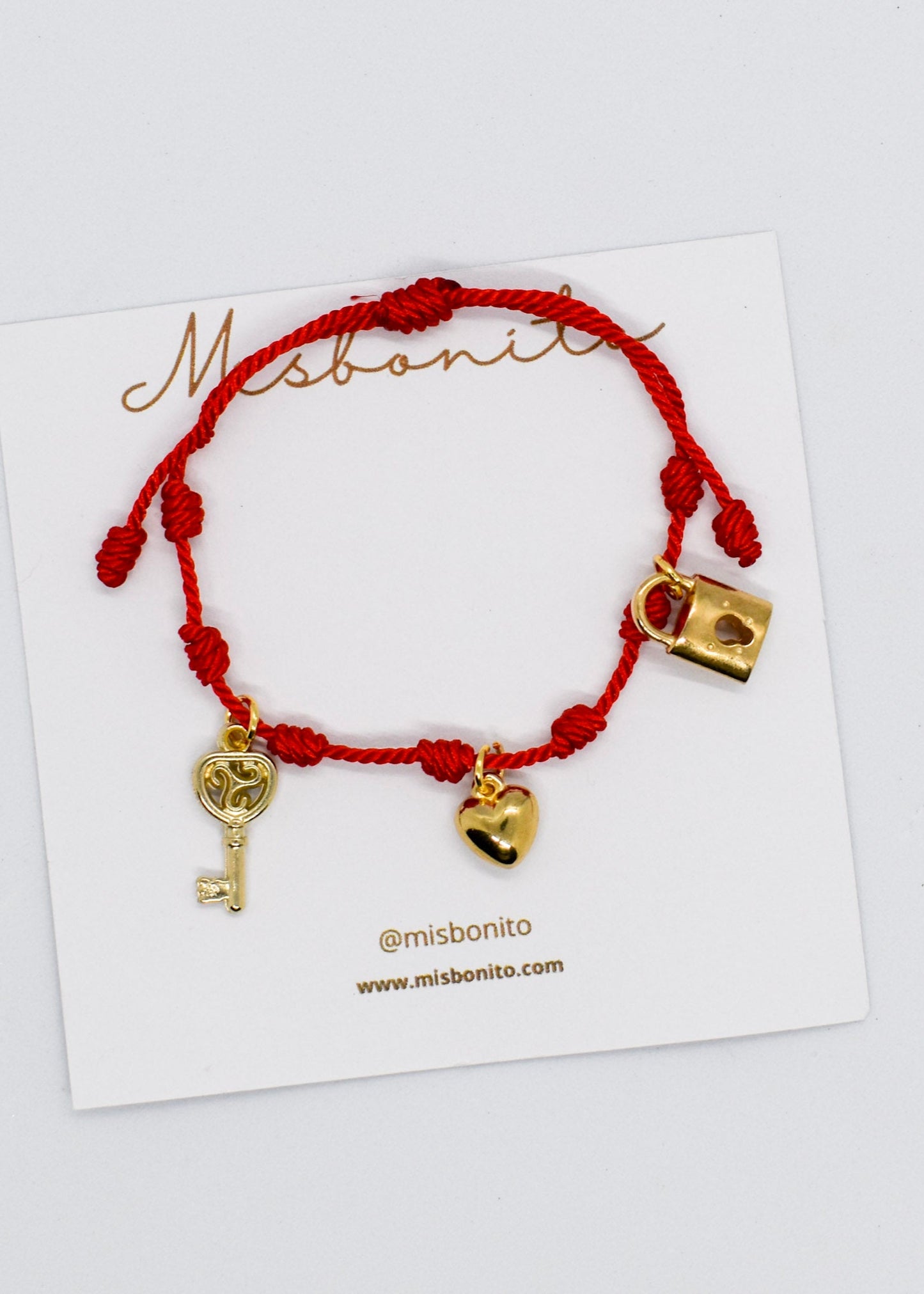 Red bracelet with gold love charms on a white card with 'misbonito' branding.