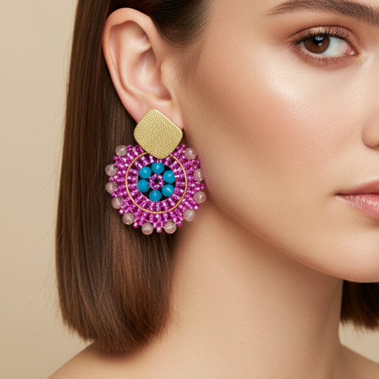 Ai model wearing a pair of beaded earrings with pink and blue design on a beige display box.