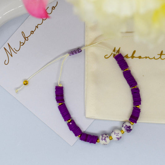 purple heishi bead with 3 beads on a misbonito branded card and pouch