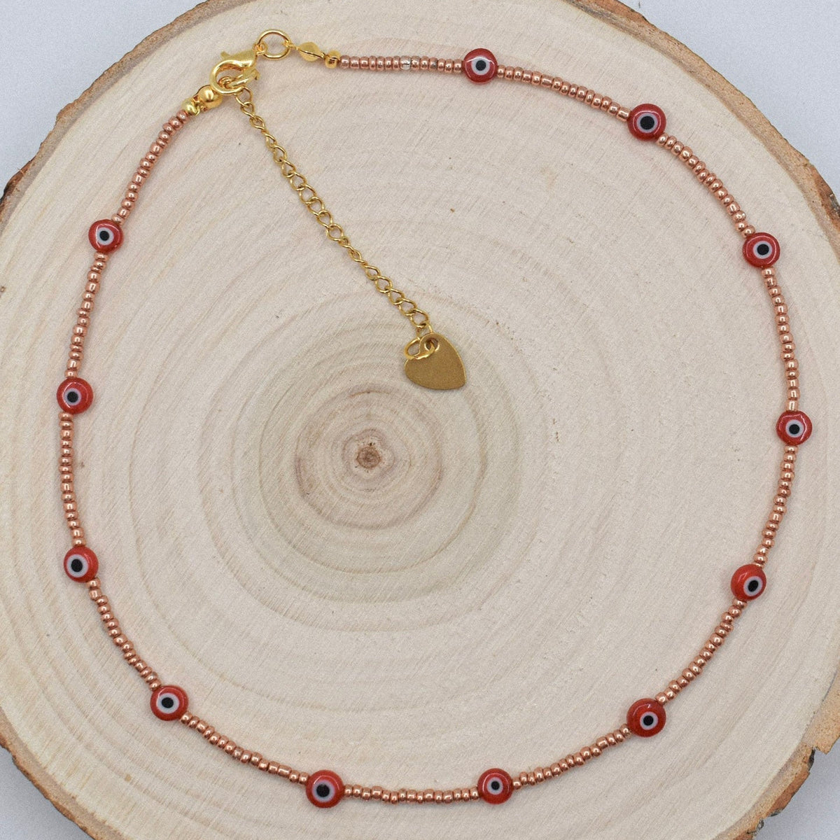 red and golden evil eye necklace choker on wood surface