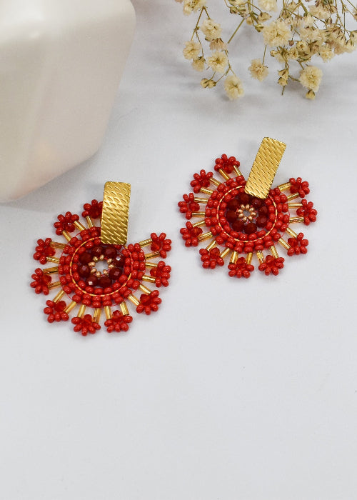 Red beaded earrings with gold accents on a white background