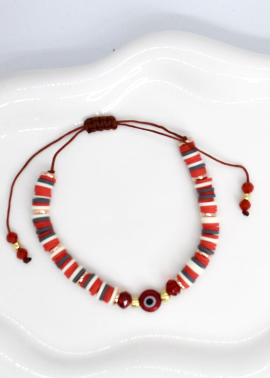 red heishi beads bracelet with evil eye bead on a white tray