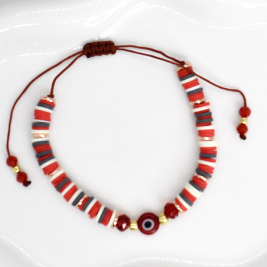 red heishi beads bracelet with evil eye bead on a white tray