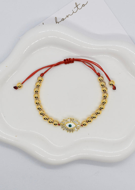 Gold beaded bracelet with a central stone on a white dish, branded 'hanita'.