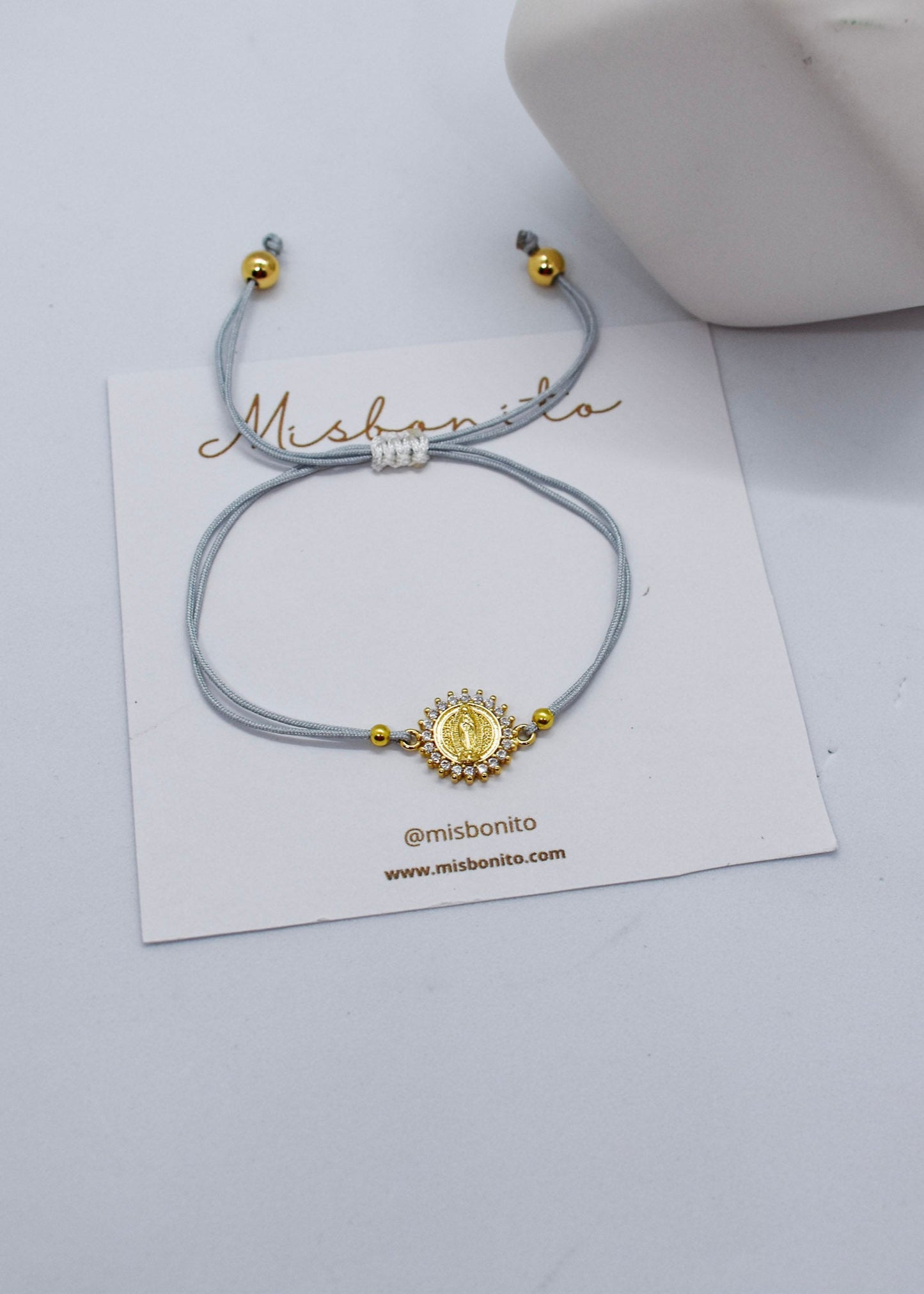 Bracelet with gold accents on a white card with 'Mishonito' branding, on a light gray background.