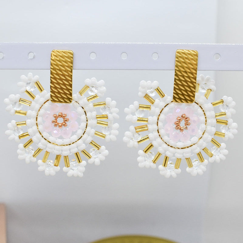 Pair of earrings with gold and white design on a light gray background