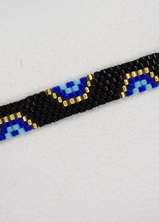 Close-up of a beaded bracelet with blue and gold accents on a light gray background