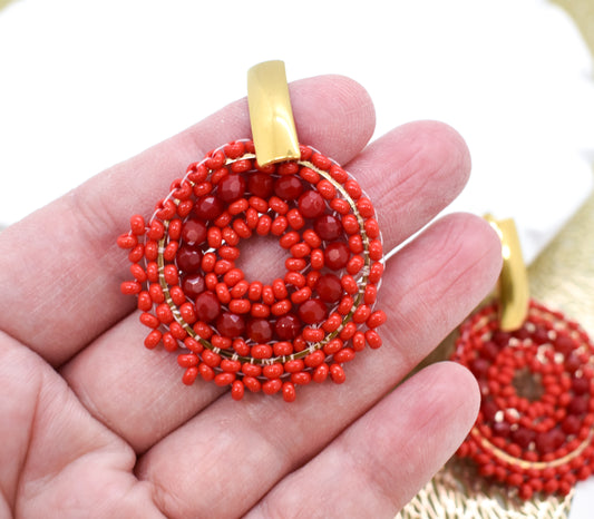 A hand holding a pair of Red earrings 