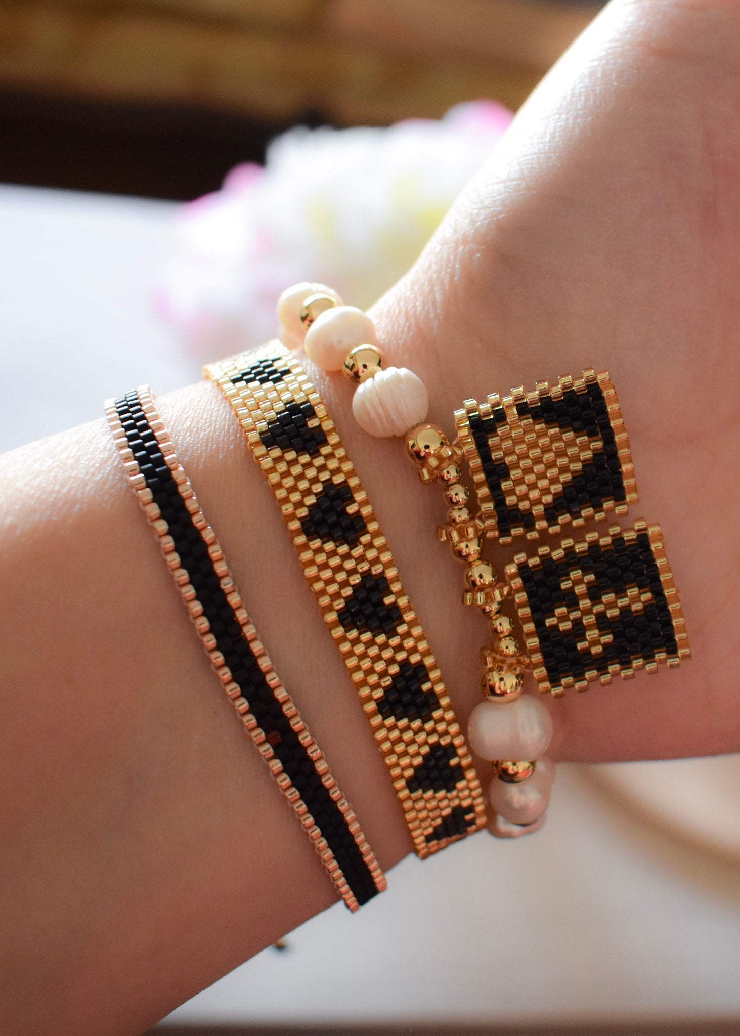 Close-up of a hand wearing multiple beaded bracelets with geometric patterns.