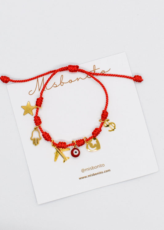 Red braided bracelet with gold charms on a Misbaha branded card.