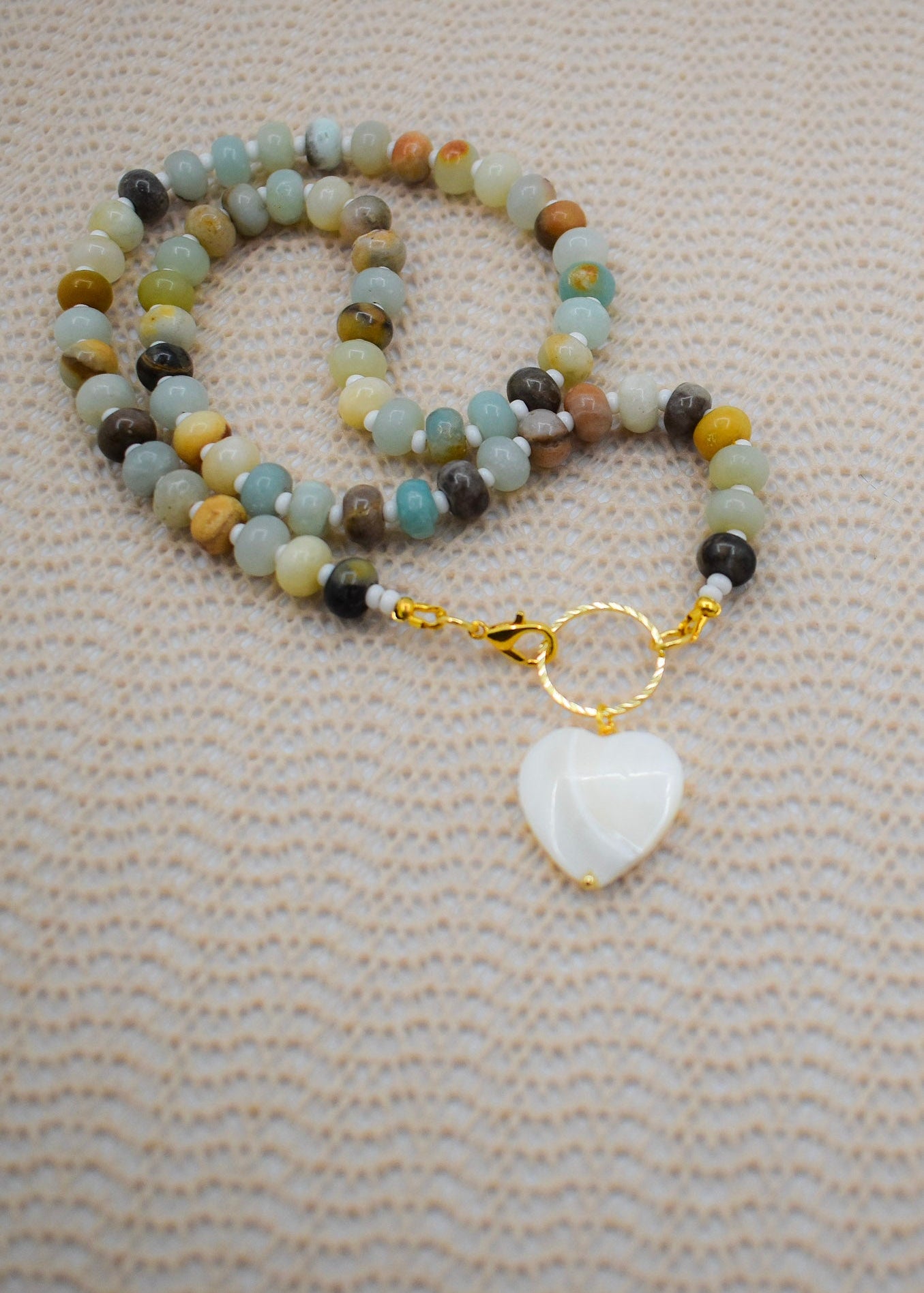 A beaded necklace with natural abacus amazonite stones and a white mother pearl heart