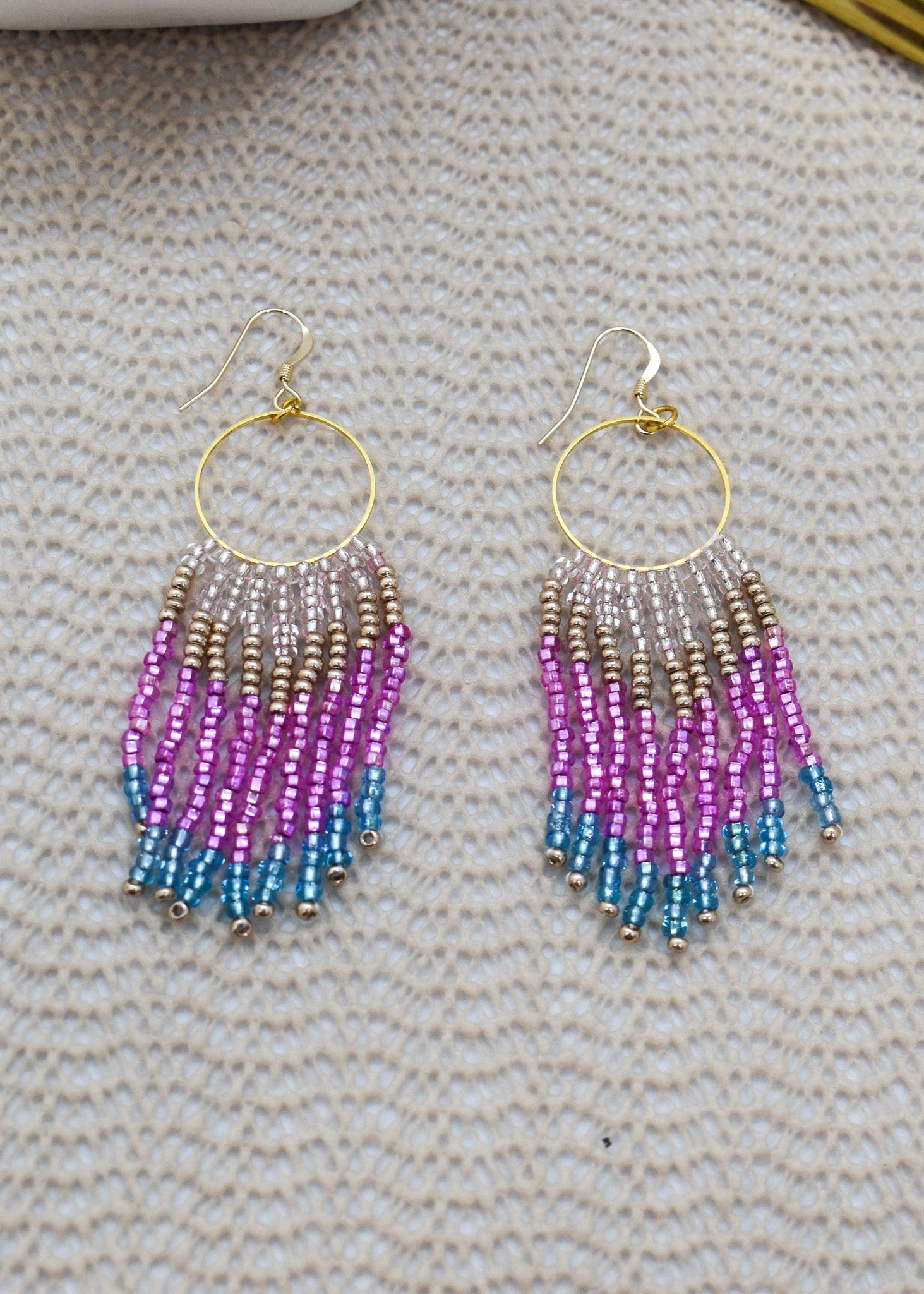 Beaded earrings with gradient colors on a textured surface