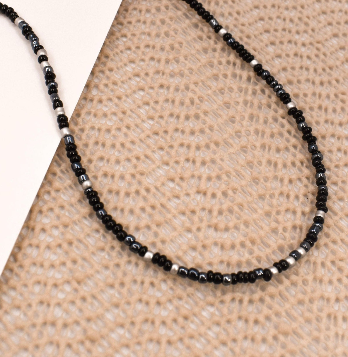 Black beaded necklace on a textured surface