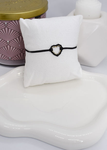 Black beaded heart bracelet on a white pillow 