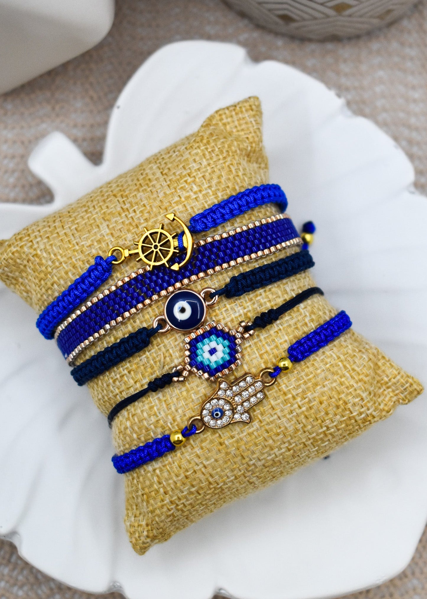 Set of blue and gold bracelets on a decorative yellow pillow with a shell background