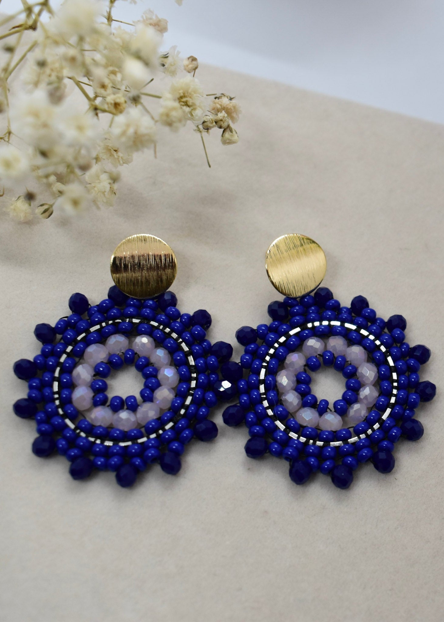 Pair of blue beaded earrings with gold accents on a light background