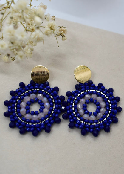 Pair of blue beaded earrings with gold accents on a light background