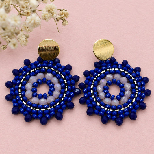 Pair of blue beaded earrings with gold accents on a light background