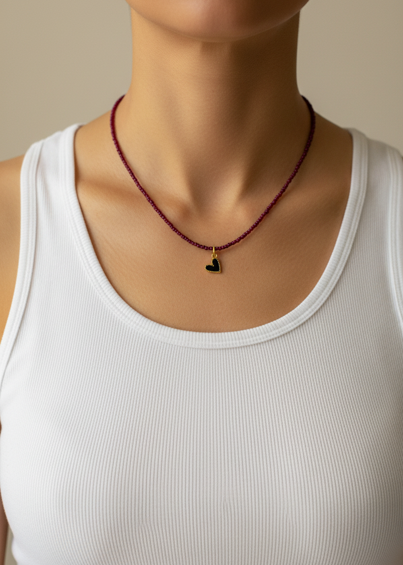 Person wearing a red beaded necklace with a heart pendant on a beige background