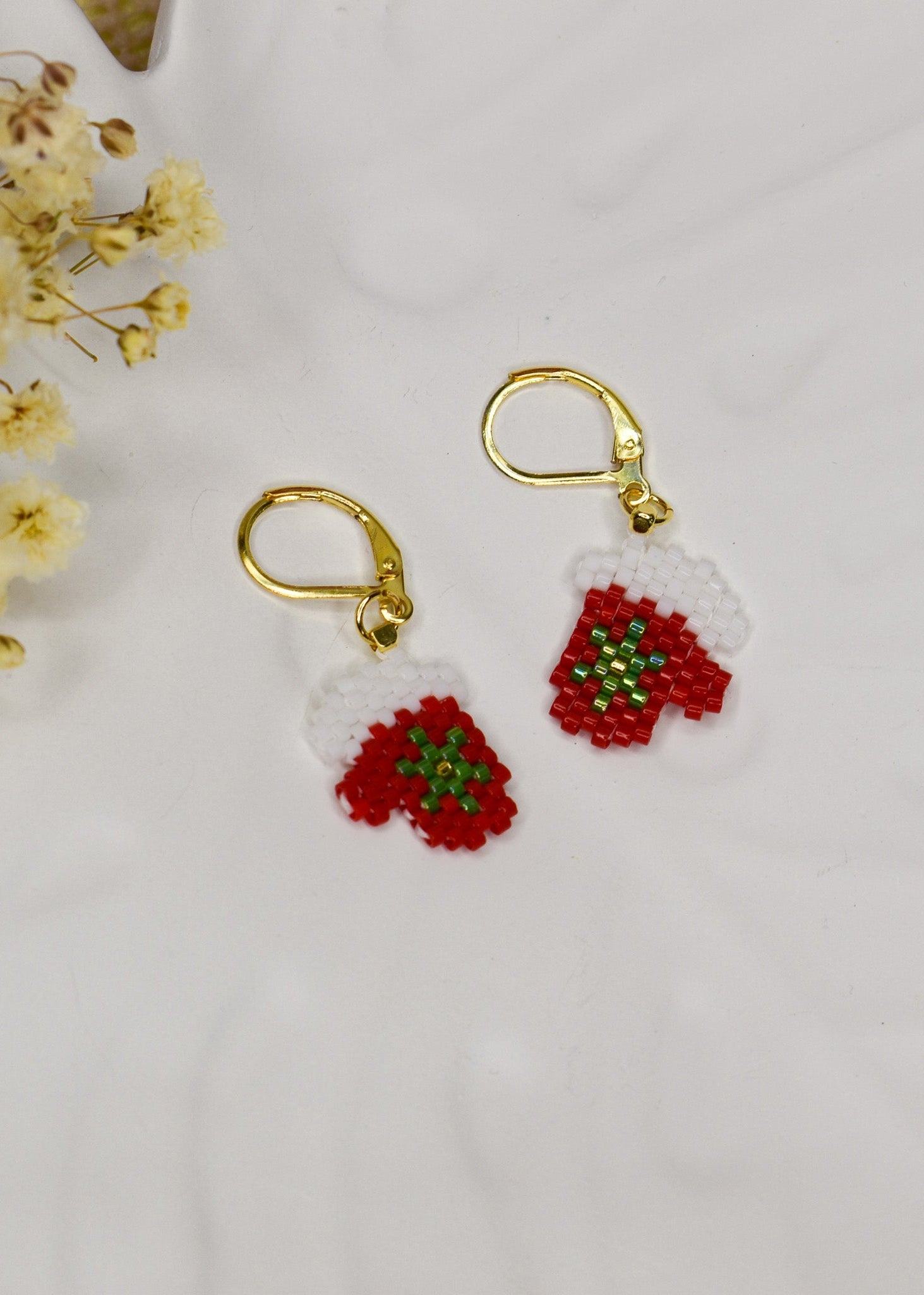 Gold earrings with red Christmas mitten on white background