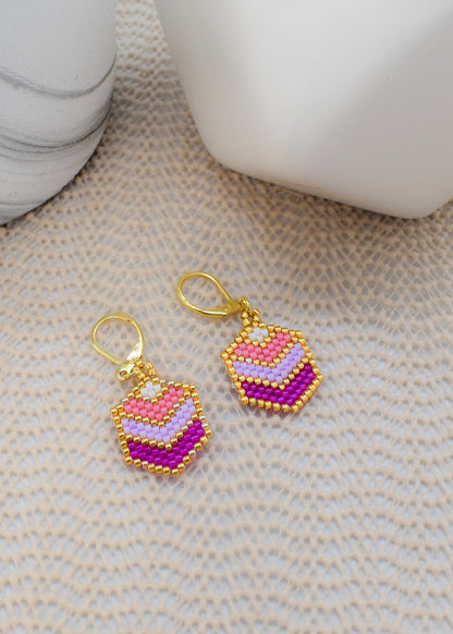 Colorful beaded earrings on a textured surface with a blurred background