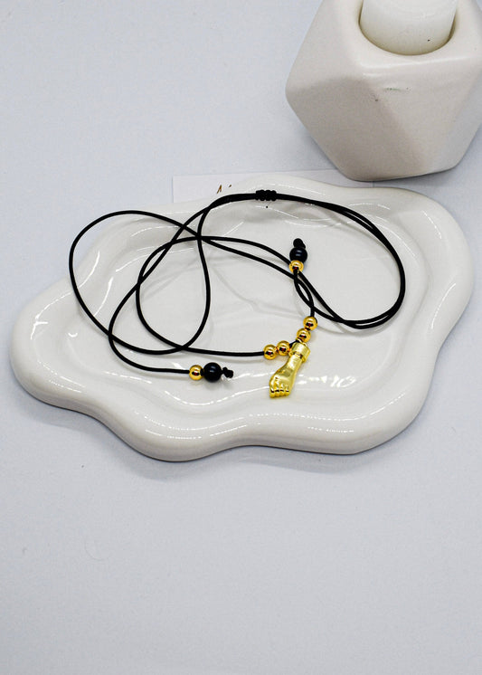 Hand necklace on a white ceramic dish with a plain background