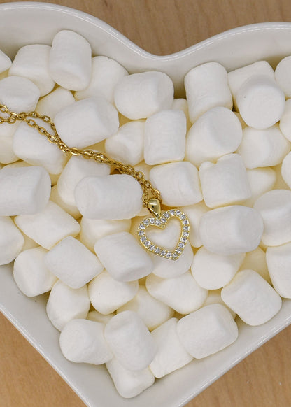Heart-shaped dish filled with marshmallows and a gold necklace on a wooden surface