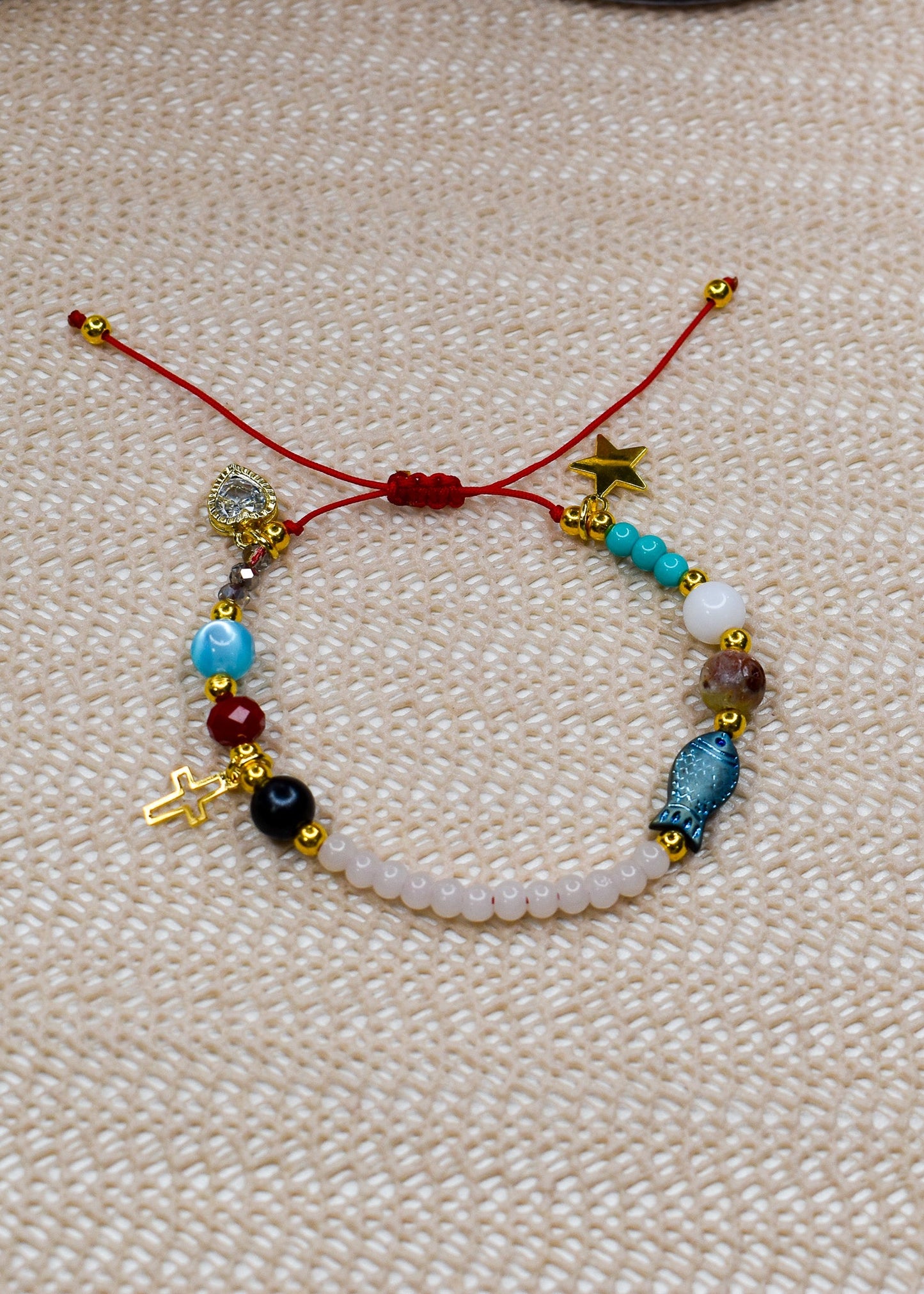 Beaded bracelet with charms on a textured beige surface