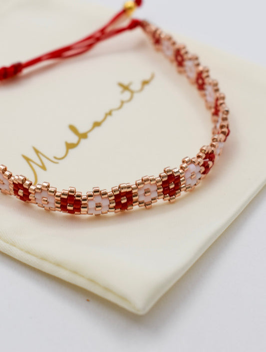 Bracelet with red and gold beads on a white card with 'Maturity' text
