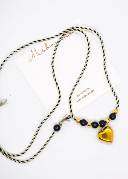 Necklace with black beads and a gold heart pendant on a white background
