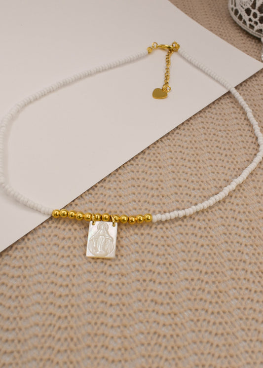 Necklace with white beads and gold accents on a textured surface