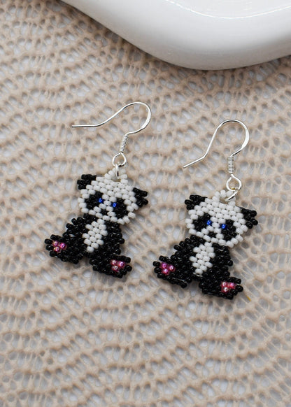 Panda-shaped beaded earrings on a textured surface