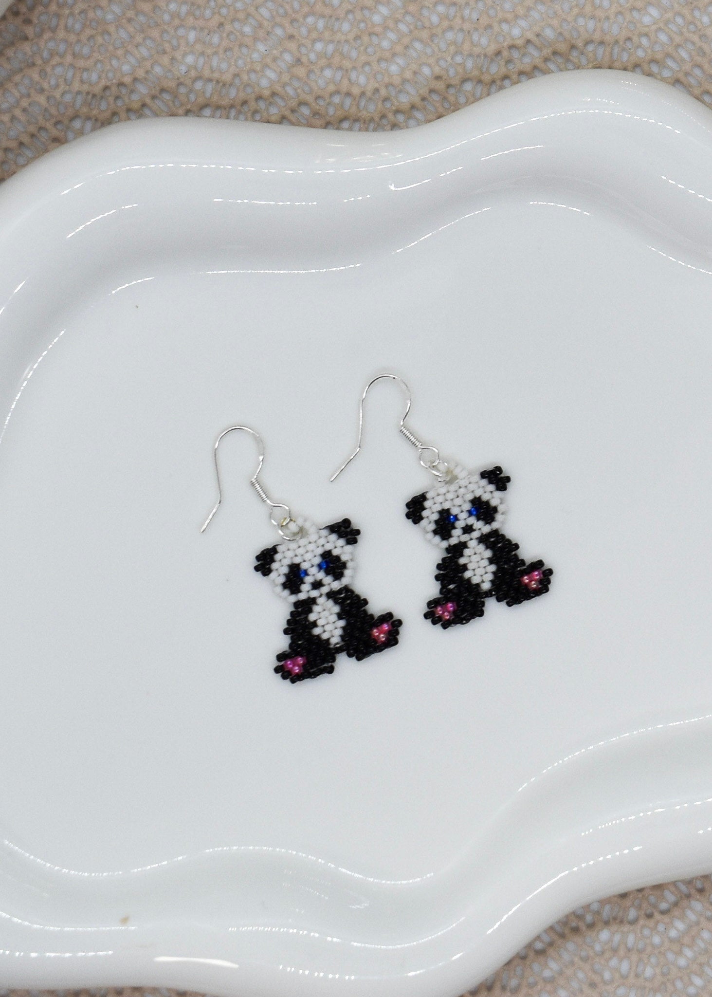 Panda-shaped beaded earrings on a white dish