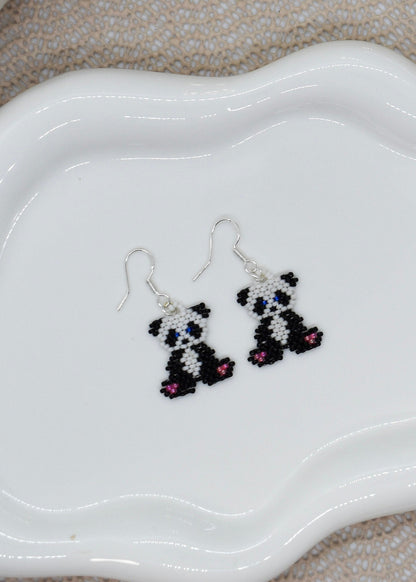 Panda-shaped beaded earrings on a white dish