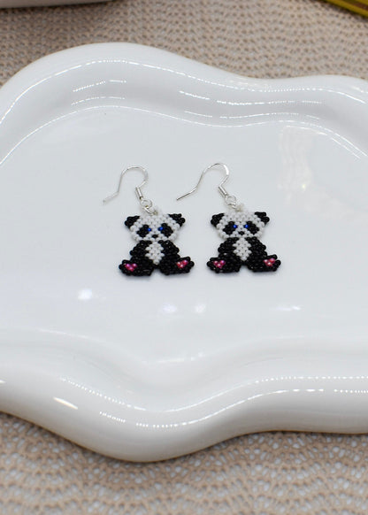 Panda-shaped earrings on a white dish with a textured surface