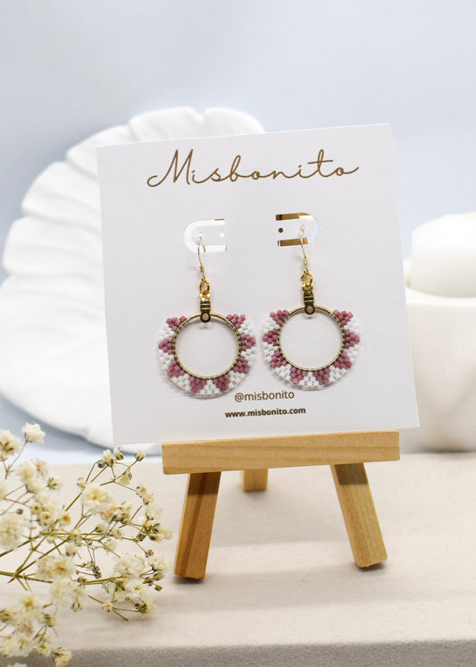 Earrings on a Misbonito branded card with a small wooden stand on a light background.
