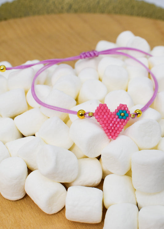 Pink beaded heart bracelet on a bed of white marshmallows