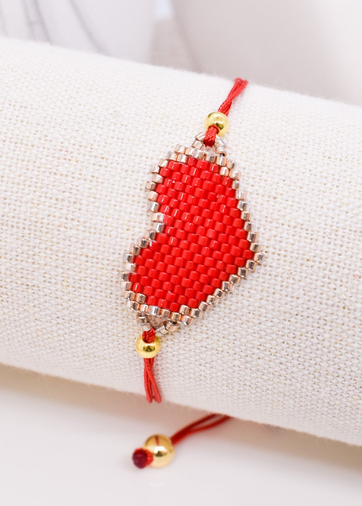 Red beaded bracelet with gold accents on a white surface