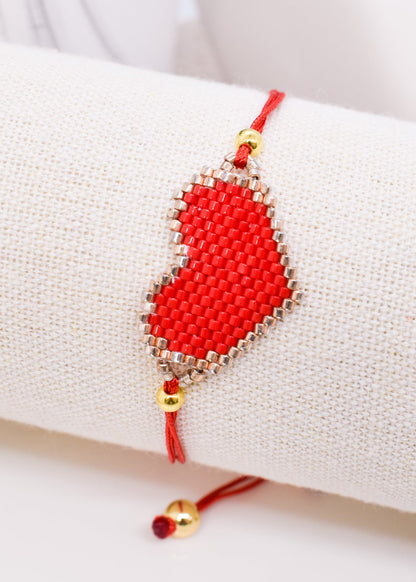 Red beaded bracelet with gold accents on a white surface