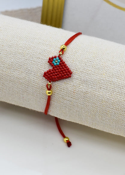 Red bracelet with decorative elements on a beige cushion