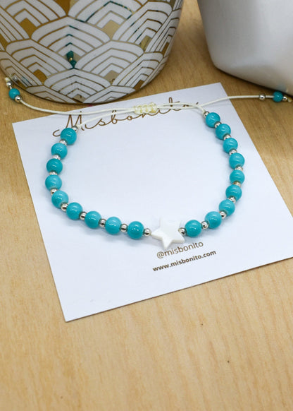 Turquoise beaded bracelet on a white card with 'Mishbonito' branding on a wooden surface.