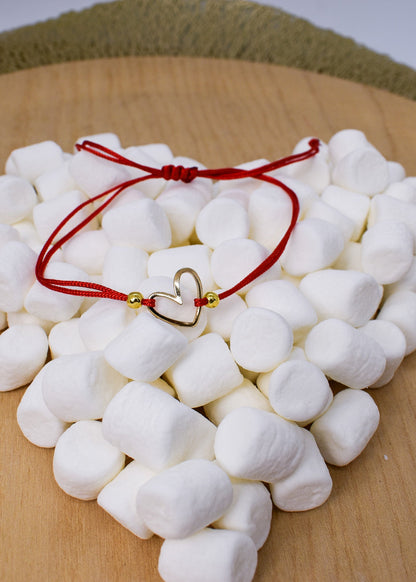 White marshmallows with a red string and gold heart charm on a wooden surface