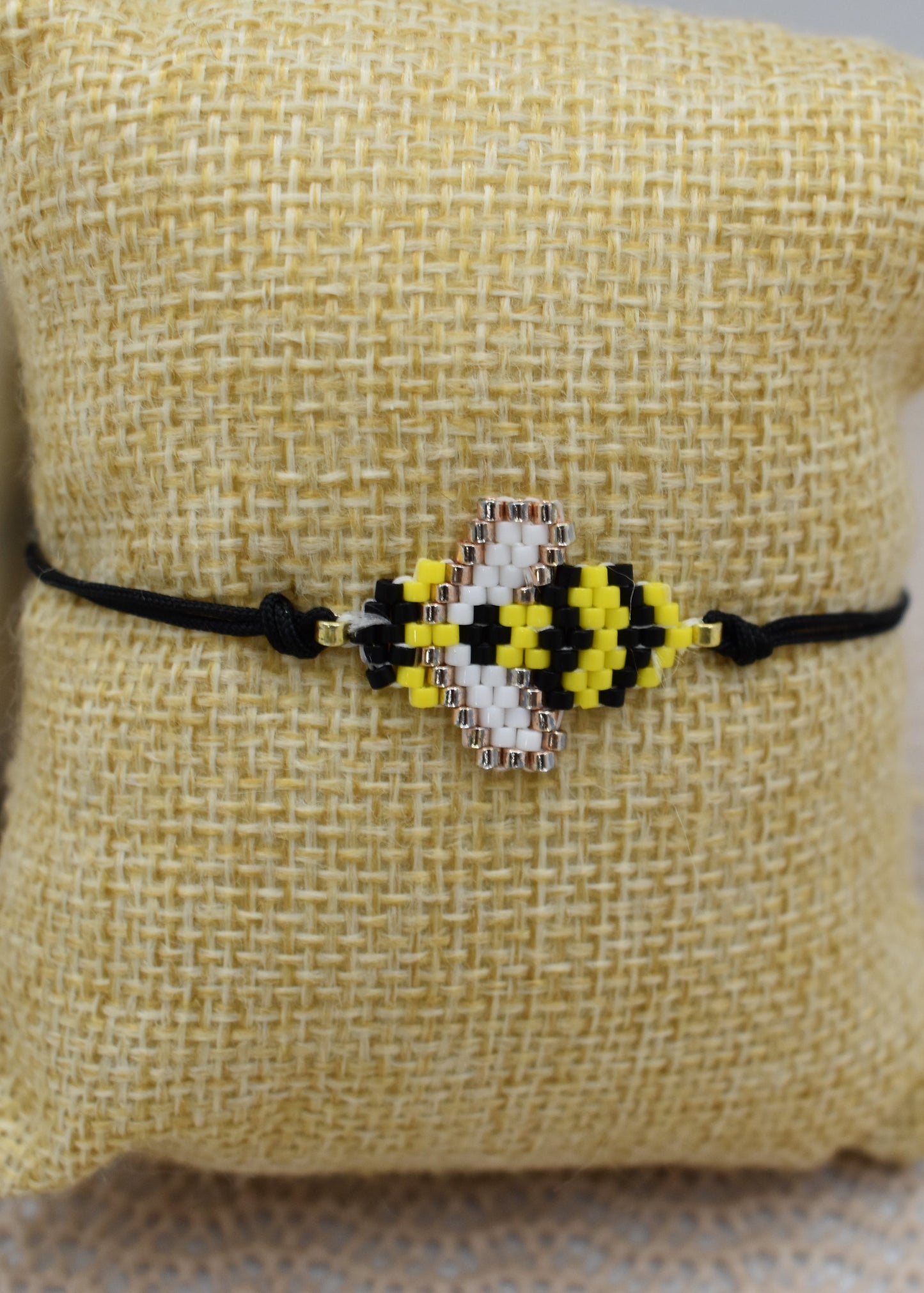 Bracelet with a bee design on a textured pillow