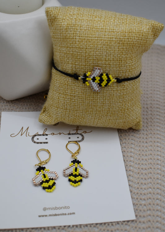 Bee-themed earrings on a card with a yellow pillow in the background