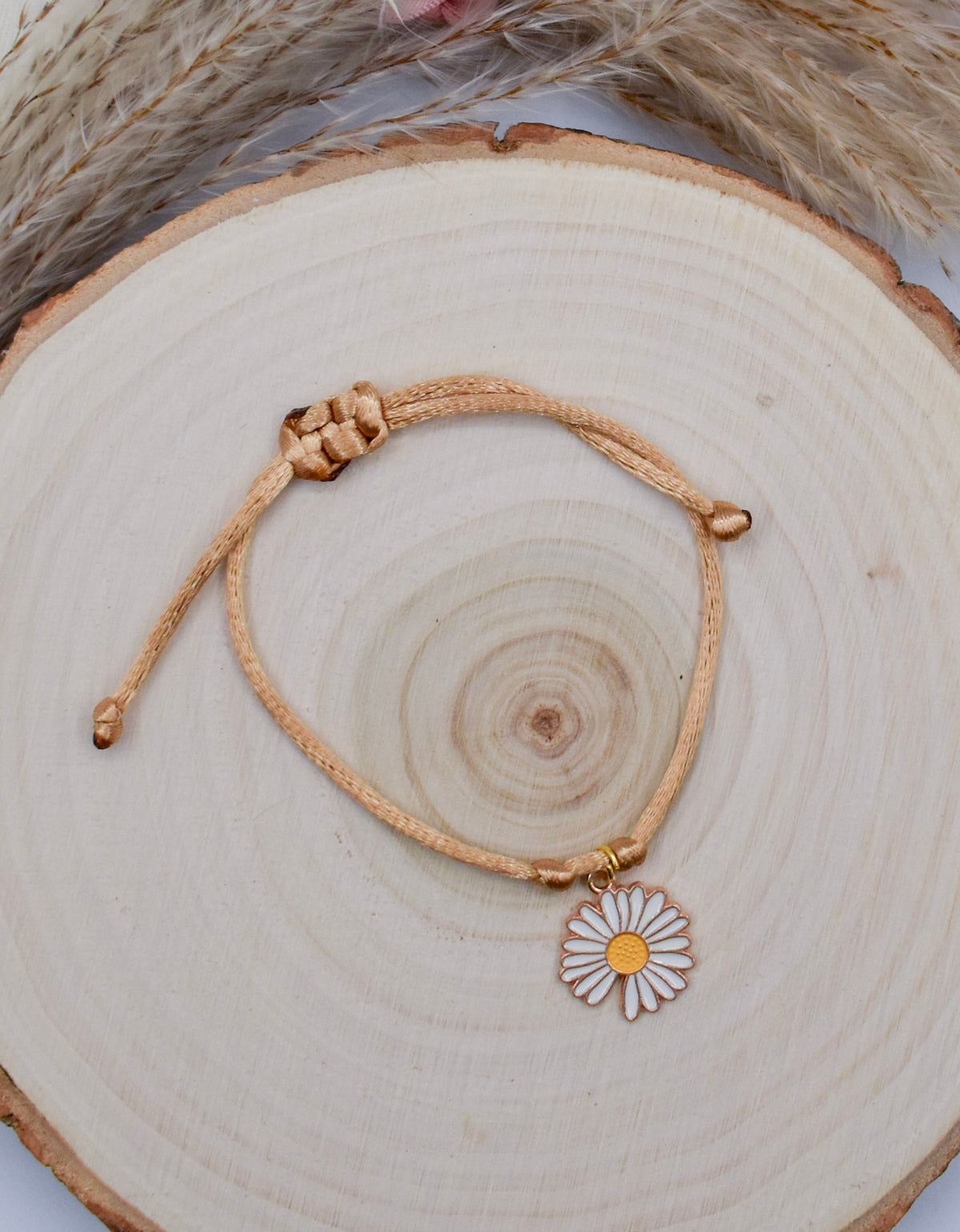 beige and daisy floral bracelet on a wood surface