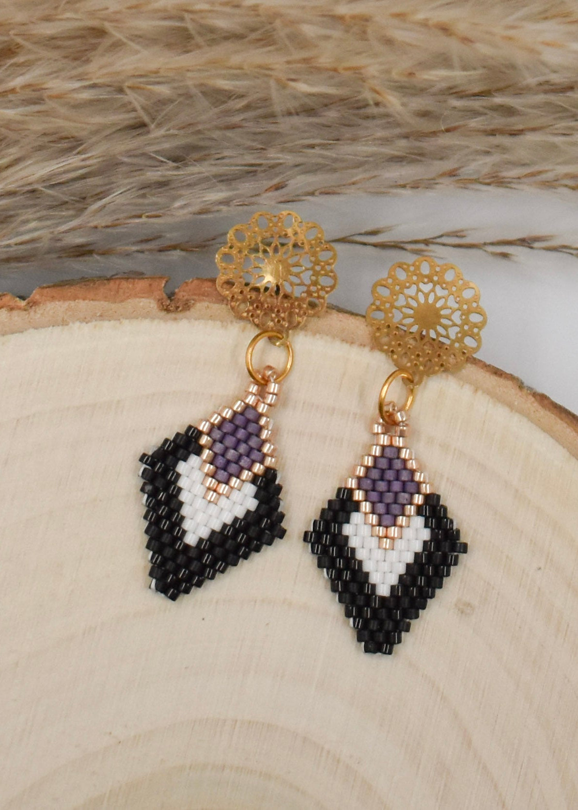 black and white diamond shaped earrings on a wood background