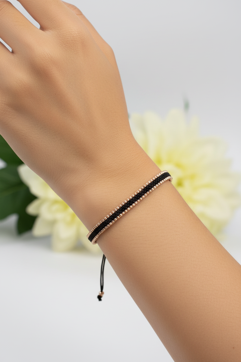 Hand wearing a black beaded bracelet with a light background