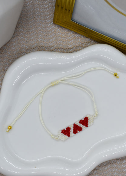 Bracelet with red heart beads on a white dish