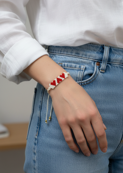 Person wearing a bracelet with a red and white pattern on a plain background