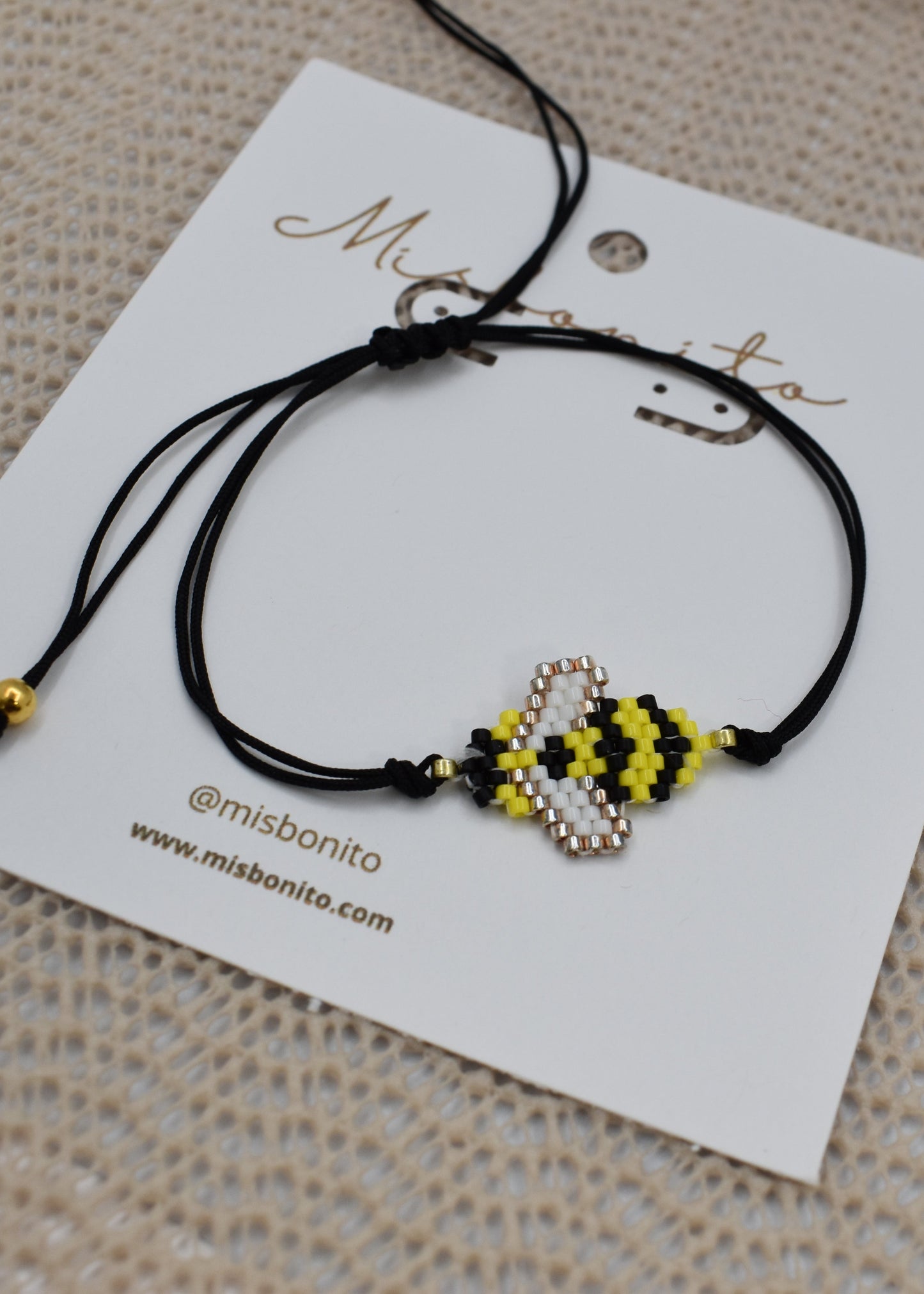 Black bracelet with bee-shaped charms on a branded card